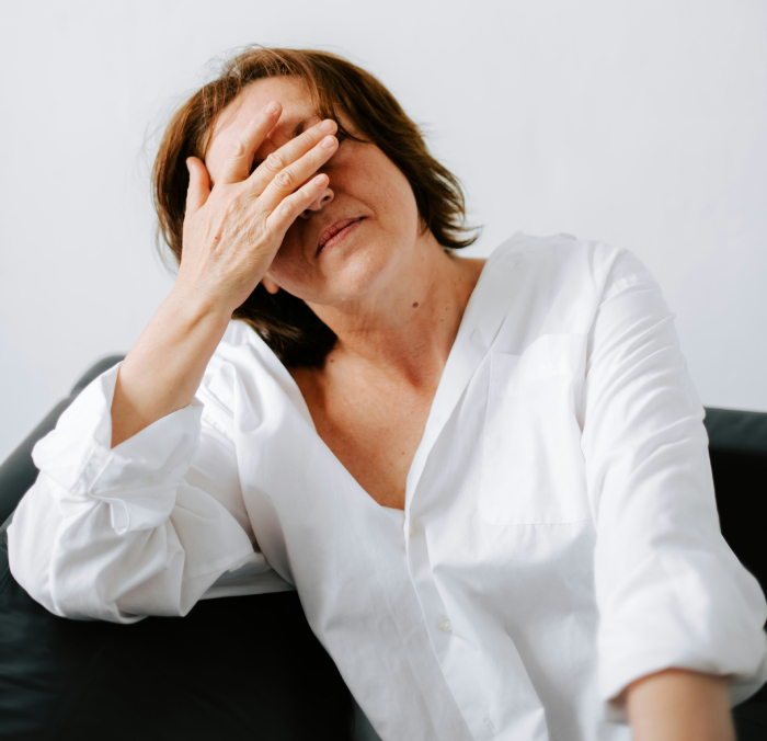 A middle aged woman with hand on her head, upset